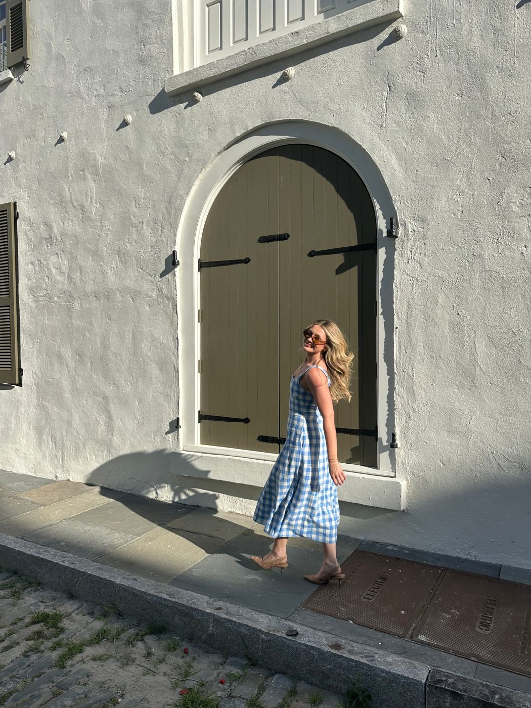 Julia Kane in a white blouse standing in an arched doorway